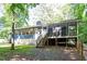Backyard view of a home with a wooden deck and steps, enveloped by lush greenery at 5124 Lazywood Ln, Durham, NC 27712