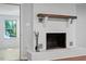 White brick fireplace with wood mantle and fireplace tools in the living room with hardwood floors at 5124 Lazywood Ln, Durham, NC 27712
