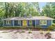 Charming blue home featuring a bright yellow front door, complemented by lush greenery for added privacy at 5124 Lazywood Ln, Durham, NC 27712