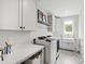 Bright laundry room featuring modern washer, dryer and white cabinets at 7304 Wexford Woods Ln, Wake Forest, NC 27587