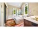 Well-appointed bathroom boasts a soaking tub, arched windows, and stylish wood-look flooring for a serene ambiance at 8200 Bromley Rd, Hillsborough, NC 27278