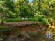 Two chairs are positioned on a cliff overlooking a calm creek at 8200 Bromley Rd, Hillsborough, NC 27278