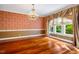 Elegant dining room featuring a decorative chandelier, custom wallpaper, large window, and hardwood floors at 8200 Bromley Rd, Hillsborough, NC 27278