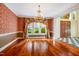 Formal dining room with hardwood floors, elegant chandelier, custom wallpaper, and views of the front yard at 8200 Bromley Rd, Hillsborough, NC 27278