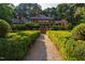 Stunning brick home exterior with lush green hedge-lined path leading to the entrance, and a wooded backdrop at 8200 Bromley Rd, Hillsborough, NC 27278