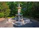 Ornate multi-tiered stone fountain featuring lion statues in a peaceful garden setting with mature trees at 8200 Bromley Rd, Hillsborough, NC 27278