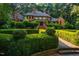 View of home exterior and lush, manicured front yard with geometric hedge design and brick staircase to entrance at 8200 Bromley Rd, Hillsborough, NC 27278