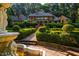 View of brick home exterior featuring a manicured front yard with geometric hedges and ornate fountain feature at 8200 Bromley Rd, Hillsborough, NC 27278