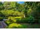 Serene garden featuring neatly trimmed hedges, mature trees, and a classic stone fountain centerpiece at 8200 Bromley Rd, Hillsborough, NC 27278