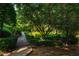 Pathway through a tranquil garden with manicured hedges, mature trees, and lush greenery, creating a peaceful retreat at 8200 Bromley Rd, Hillsborough, NC 27278