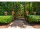 Ornate brick and iron gate leads to a private, tree-lined driveway and estate at 8200 Bromley Rd, Hillsborough, NC 27278
