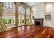 Bright living room with large windows, hardwood floors, ornate drapery, fireplace, and built-in shelving at 8200 Bromley Rd, Hillsborough, NC 27278