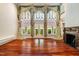 Spacious living room featuring high ceilings, hardwood floors, large windows with ornate drapery, and a fireplace at 8200 Bromley Rd, Hillsborough, NC 27278
