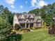 Expansive aerial view of a stone home featuring pristine landscaping and a lush tree surround at 1009 Margarets Ln, Raleigh, NC 27614