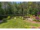 Lush backyard featuring a pergola, waterfall, mature trees, and professionally landscaped greenery at 1009 Margarets Ln, Raleigh, NC 27614