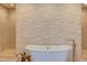 Bright bathroom featuring a freestanding tub with a stone accent wall and tiled flooring at 1009 Margarets Ln, Raleigh, NC 27614