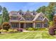 Stunning stone home with manicured lawn, dormer windows, and lush landscaping at 1009 Margarets Ln, Raleigh, NC 27614