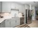 Close-up of a well-lit kitchen featuring stainless steel appliances, white backsplash and gray cabinets at 105 Chatham Walk Ln # 304, Cary, NC 27511