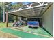 A covered carport with vehicles and a boat, adjacent to a lush green yard at 109 Mill Creek Dr, Youngsville, NC 27596