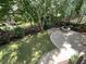 Landscaped backyard featuring a stone firepit and patio nestled among mature trees and lush greenery at 1316 Plunket Dr, Wake Forest, NC 27587