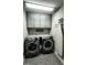 Modern laundry room with gray cabinets and gray front loading washer and dryer at 192 Waterpine Dr, Garner, NC 27529