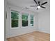Bright bedroom featuring a ceiling fan and three windows overlooking lush greenery, complemented by hardwood floors at 2810 Bedford Green Dr # 5, Raleigh, NC 27604
