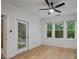 Bright bedroom featuring a ceiling fan, hardwood floors, and three windows overlooking lush greenery, with a door to the outside at 2810 Bedford Green Dr # 5, Raleigh, NC 27604
