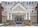 Close-up of a condo building entrance featuring stone pillars, glass doors, and well-maintained landscaping at 2810 Bedford Green Dr # 5, Raleigh, NC 27604