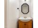 Half bathroom featuring a honey stained vanity, octagon mirror and a classic white countertop sink at 3421 Tunas St, Raleigh, NC 27616