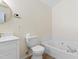 Bathroom featuring a tile-trimmed soaking tub, toilet, and vanity with white cabinets and gold faucet at 3421 Tunas St, Raleigh, NC 27616