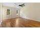 Well-lit bedroom featuring hardwood floors, ceiling fan, and large windows overlooking the backyard at 3421 Tunas St, Raleigh, NC 27616