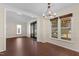 An open dining room with dark wood flooring, updated chandelier, and windows with dark-toned shades at 3421 Tunas St, Raleigh, NC 27616