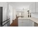 Open kitchen with stainless steel fridge, white cabinets, and a view into the dining and living areas at 3421 Tunas St, Raleigh, NC 27616
