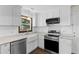 Bright, updated kitchen featuring white cabinetry, stainless steel appliances, and elegant finishes at 3421 Tunas St, Raleigh, NC 27616