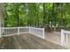 Wooden back deck with white railing overlooking a serene wooded backyard, perfect for relaxation and outdoor enjoyment at 40 Raccoon Xing, Henderson, NC 27537