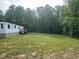 Side view of the house with a grassy lawn and forest in the background at 4025 Royal Dr, Franklinton, NC 27525