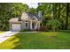 Charming home features a manicured lawn, shrubbery, garage, and mature trees at 4117 Olde Coach Rd, Durham, NC 27707