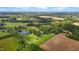 Expansive aerial view of a property featuring lush greenery, a serene pond, and farmland at 4345 Mcintyre Rd, Gibsonville, NC 27249