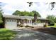 View of the home's rear exterior, featuring a brick facade, white garage door, and a charming deck with a white railing at 4345 Mcintyre Rd, Gibsonville, NC 27249