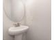 Clean half bathroom with a pedestal sink and a round mirror at 454 Martins Mill Ct, Wendell, NC 27591