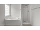 Bright bathroom features a soaking tub, a stand up shower, and beige tile flooring at 4716 Miller Dr, Durham, NC 27704