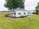 Charming white farmhouse with a metal roof and a spacious front yard surrounded by mature trees at 5004 Us 70 Alt, Princeton, NC 27569