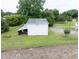 An outbuilding sits in a yard with trees in a field of crops at 5004 Us 70 Alt, Princeton, NC 27569