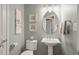 Well-lit powder room featuring a pedestal sink, oval mirror, and decorative artwork at 621 Aylestone Dr, Cary, NC 27519