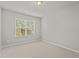 An empty, carpeted bedroom with a window, showing natural light and neutral tones at 8323 Yaxley Hall Dr, Raleigh, NC 27616