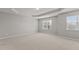 Large empty bedroom with plush carpet, neutral walls, tray ceiling and natural light at 8323 Yaxley Hall Dr, Raleigh, NC 27616