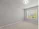 A sunlit, empty bedroom with carpet and a large window with blinds at 8323 Yaxley Hall Dr, Raleigh, NC 27616