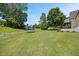 Wide open backyard features a lush lawn, mature trees, and an enclosed trampoline area at 940 Rivers Edge Dr, Graham, NC 27253