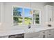 Kitchen sink with a backyard view through a large window, featuring white cabinets and modern fixtures at 940 Rivers Edge Dr, Graham, NC 27253