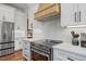 Close-up of gourmet kitchen with stainless steel range, white cabinetry, and stylish vent hood at 940 Rivers Edge Dr, Graham, NC 27253